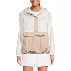 A woman is wearing a color-blocked hooded windbreaker with a large front pocket. The jacket is beige and white, paired with white shorts.
