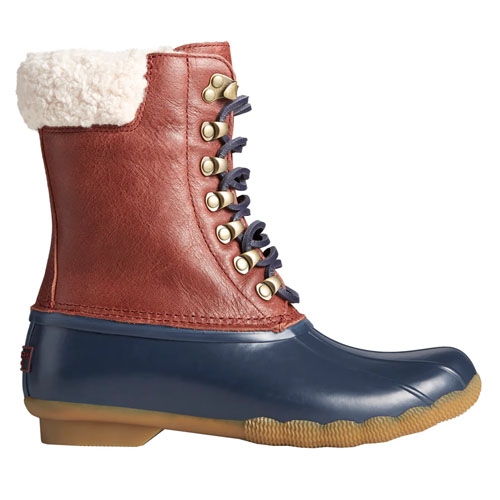 Sperry Leather Saltwater Duck Boots feature a brown leather shaft with white fleece lining, navy rubber lower section, and a tan rubber sole. The boots have metallic eyelets with dark laces, combining style with function for wet conditions.