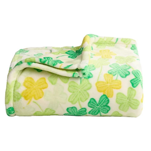 A folded fleece blanket featuring a pattern of yellow and green clovers on a white background.
