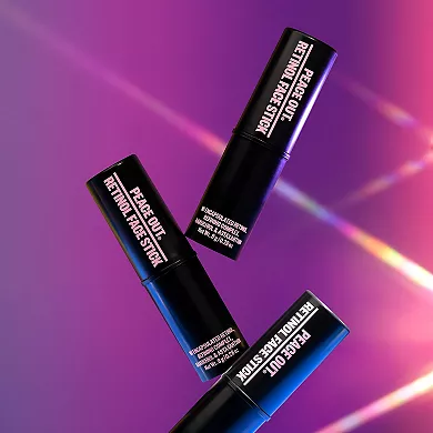 Two cylindrical containers with caps, labeled \“PEACE OUT RETINOL FACE STICK,\“ are positioned in an X shape against a purple backdrop.