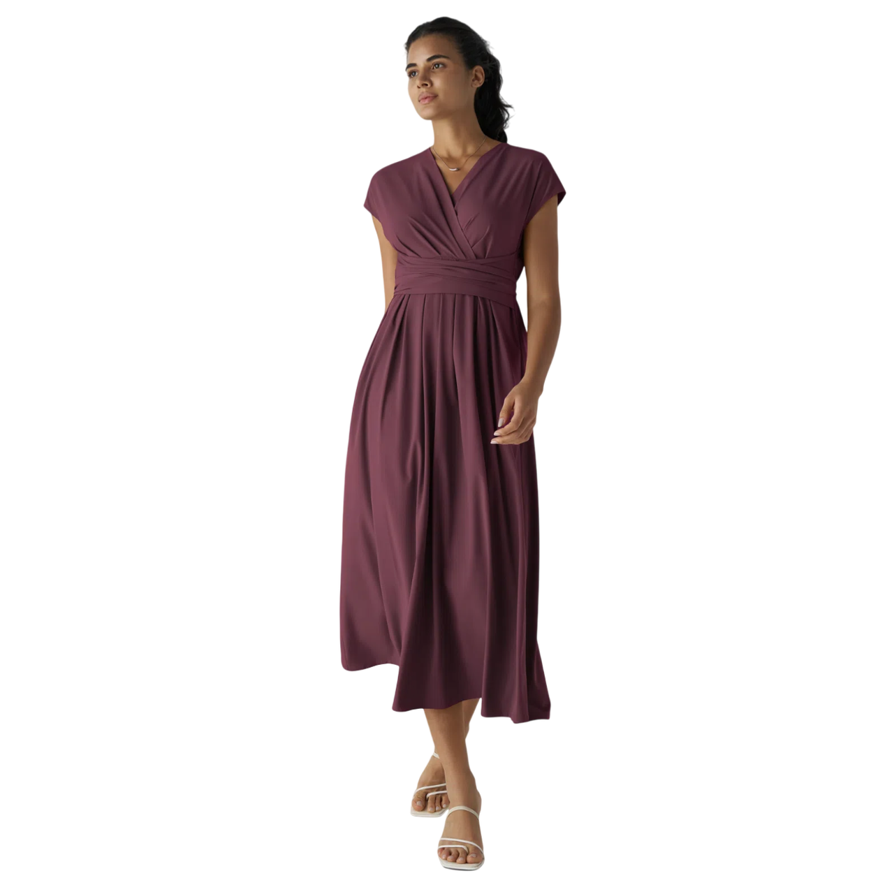 A woman is wearing a plum-colored, V-neck, short-sleeve wrap dress with an empire waist, paired with white strappy sandals.