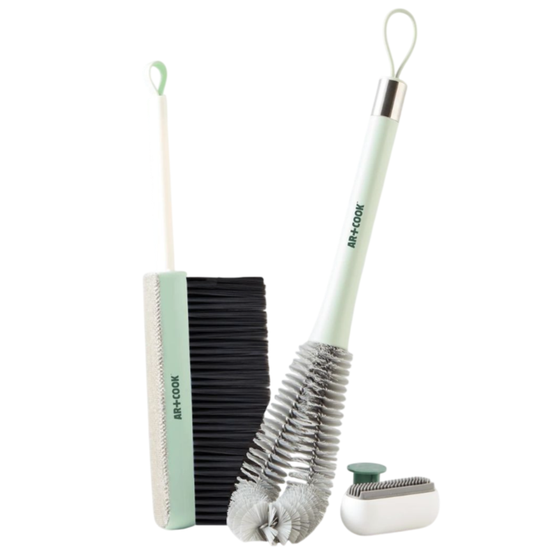 Three cleaning tools: a slim broom with a squeegee edge, a flexible bottle brush, and a compact lint roller, all with pastel green handles and loops for hanging.