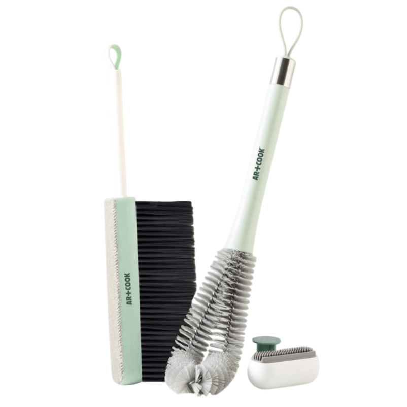 Three cleaning tools: a slim broom with a squeegee edge, a flexible bottle brush, and a compact lint roller, all with pastel green handles and loops for hanging.