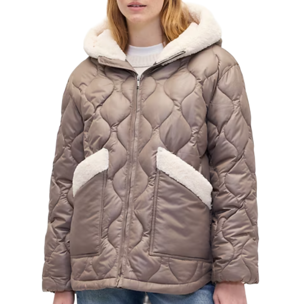 Taupe quilted jacket with a hood, featuring shearling-lined pockets and cuffs, worn over a white sweater paired with jeans.