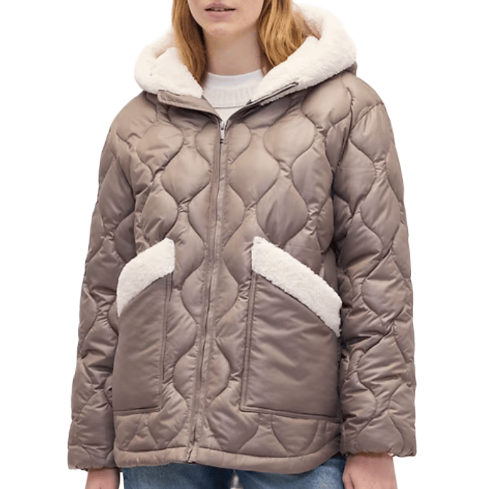 Taupe quilted jacket with a hood, featuring shearling-lined pockets and cuffs, worn over a white sweater paired with jeans.