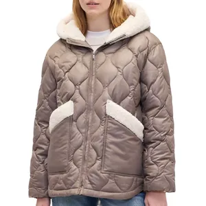 Taupe quilted jacket with a hood, featuring shearling-lined pockets and cuffs, worn over a white sweater paired with jeans.