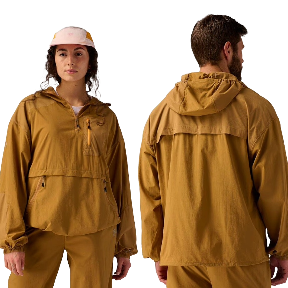 The Backcountry MTN Air Anorak is a lightweight, mustard-colored jacket with a hood and a half-zip front. It features a chest zipper pocket and side pockets, offering a relaxed fit suitable for outdoor activities.