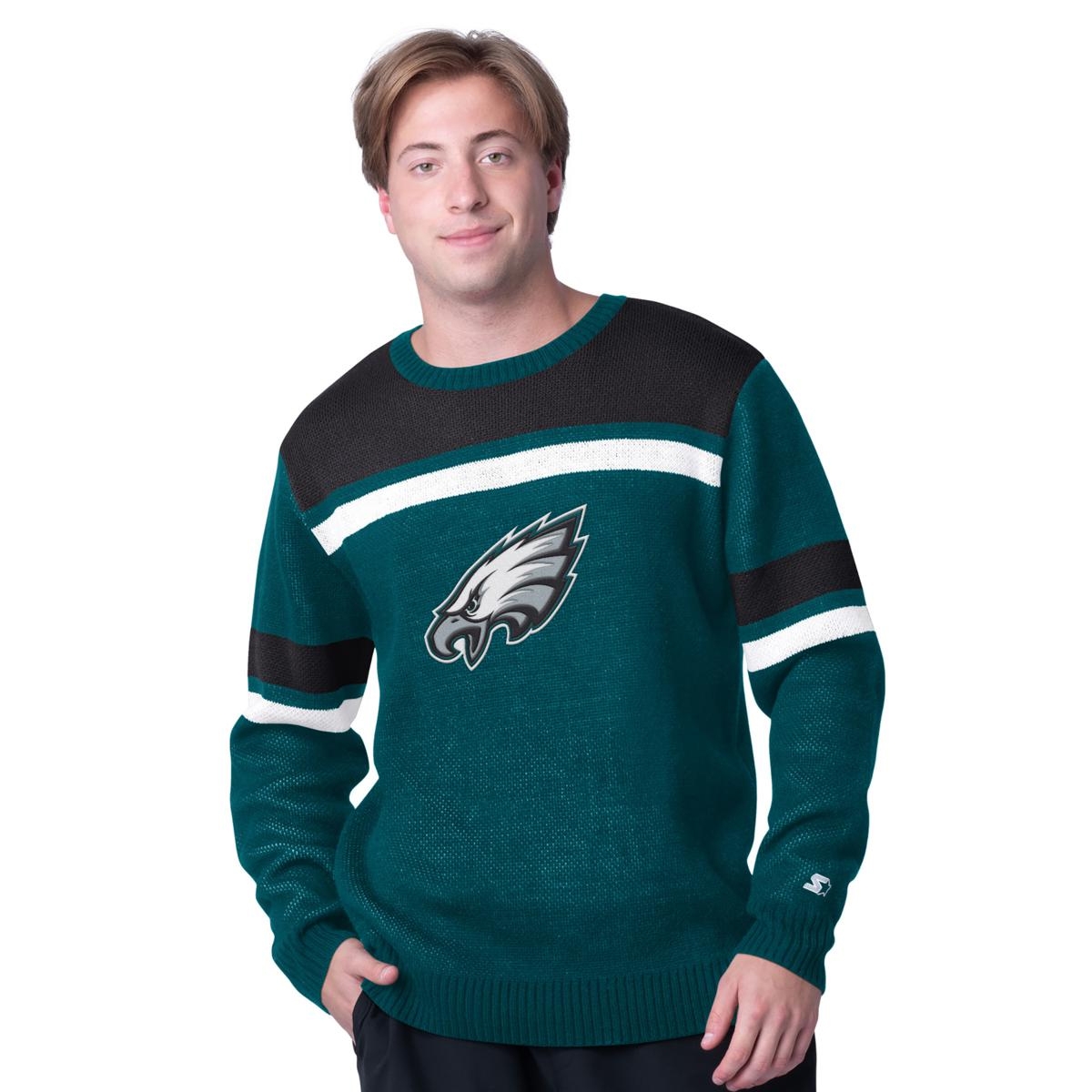 A person wearing a green sweater with a black and white stripe pattern featuring a team's eagle logo on the chest and small branding on the left sleeve cuff.