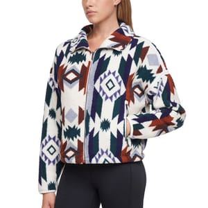A woman is wearing a fleece jacket with a geometric pattern in white, purple, green, and brown, paired with black leggings.