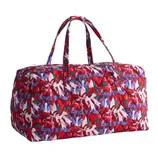 A quilted duffel bag with a colorful bow pattern in shades of red, purple, and white, featuring two handles for carrying.