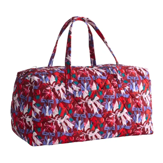 A quilted duffel bag with a colorful bow pattern in shades of red, purple, and white, featuring two handles for carrying.