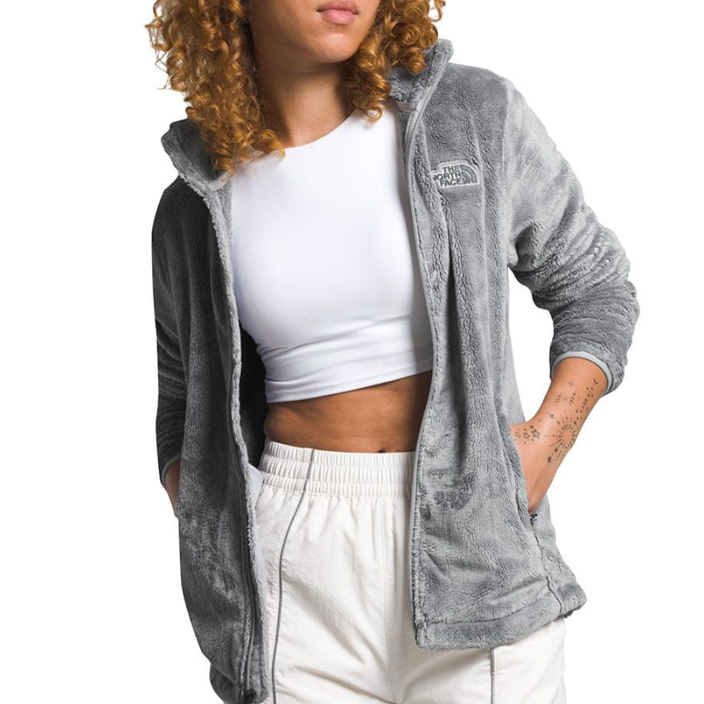 A person wearing a grey The North Face fleece jacket over a white crop top and light-colored pants.