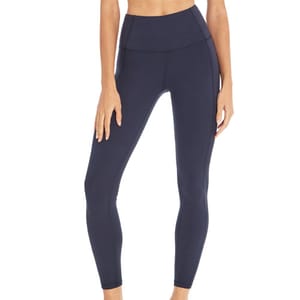 A person is modeling a pair of high-waisted, ankle-length, navy-colored leggings, focusing on their fit and style.