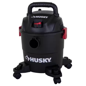 A black Husky brand wet/dry vacuum cleaner with red accents and caster wheels.