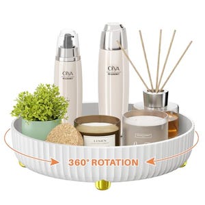A white Lazy Susan organizer displays skincare bottles, a potted plant, candles, and aroma reeds on a 360-degree rotating base.
