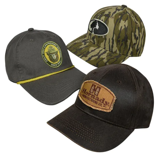 Three caps are shown: one dark with a \“Smokey Bear\“ patch and yellow cord, a camo hat with a tree logo, and a brown cap with a \“Hornady\“ patch.
