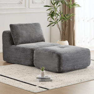 A sectional piece with a gray, corduroy-like texture including a low backrest and matching ottoman is situated on a light-speckled rug. In the background, there's a potted plant and light streaming through sheer curtains.