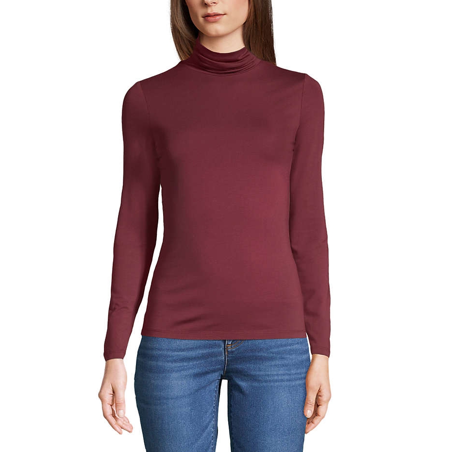 A woman is wearing a burgundy turtleneck long-sleeve top paired with blue jeans.