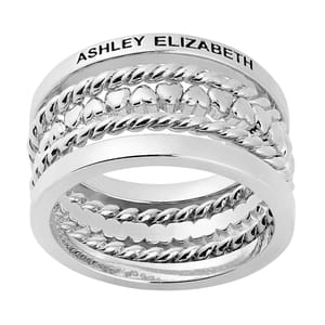 A silver multi-band ring features intricate braided and heart-shaped designs, with the name \“Ashley Elizabeth\“ engraved on the outer band.