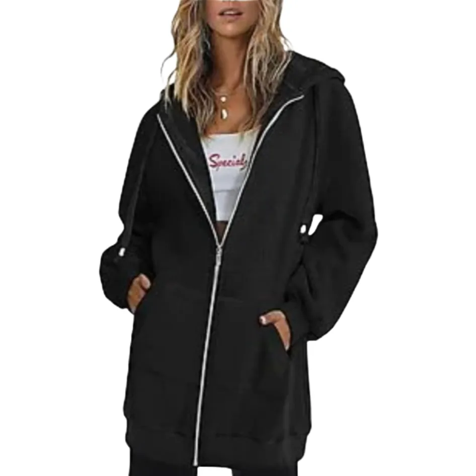 A woman is wearing a black zip-up hoodie over a white crop top with red text. The hoodie features a hood, front pockets, and long sleeves.