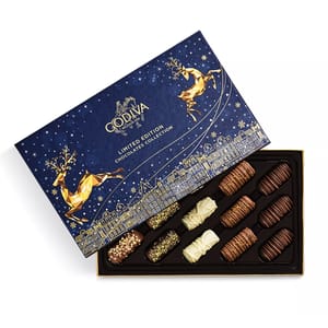 A box of Godiva Limited Edition Chocolates Collection with an elegant blue and gold design featuring geometric reindeer and cityscape, containing assorted chocolates in a tray.