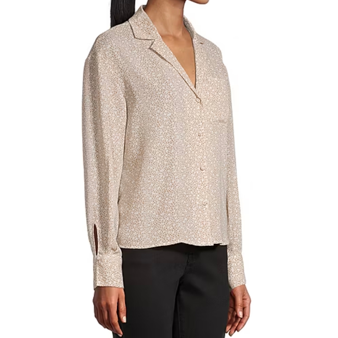 A woman is wearing a long-sleeve, collared button-up blouse with a subtle, light floral pattern, paired with black pants.