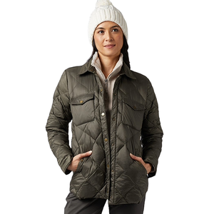 A person wears an olive green quilted jacket with snap buttons and front pockets, paired with a white knit winter hat.