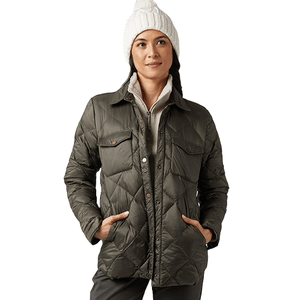 A person wears an olive green quilted jacket with snap buttons and front pockets, paired with a white knit winter hat.