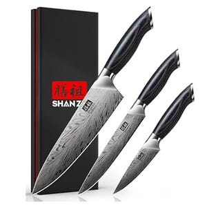 Three kitchen knives with Damascus-style patterns are shown alongside a black box labeled \“Shanz.\“