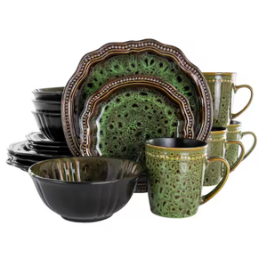 Green and black ceramic dinnerware set including plates, bowls, and mugs with a textured, speckled design and decorative edging.