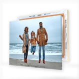 A canvas print featuring a joyful family of three jumping on a beach, with the ocean in the background.