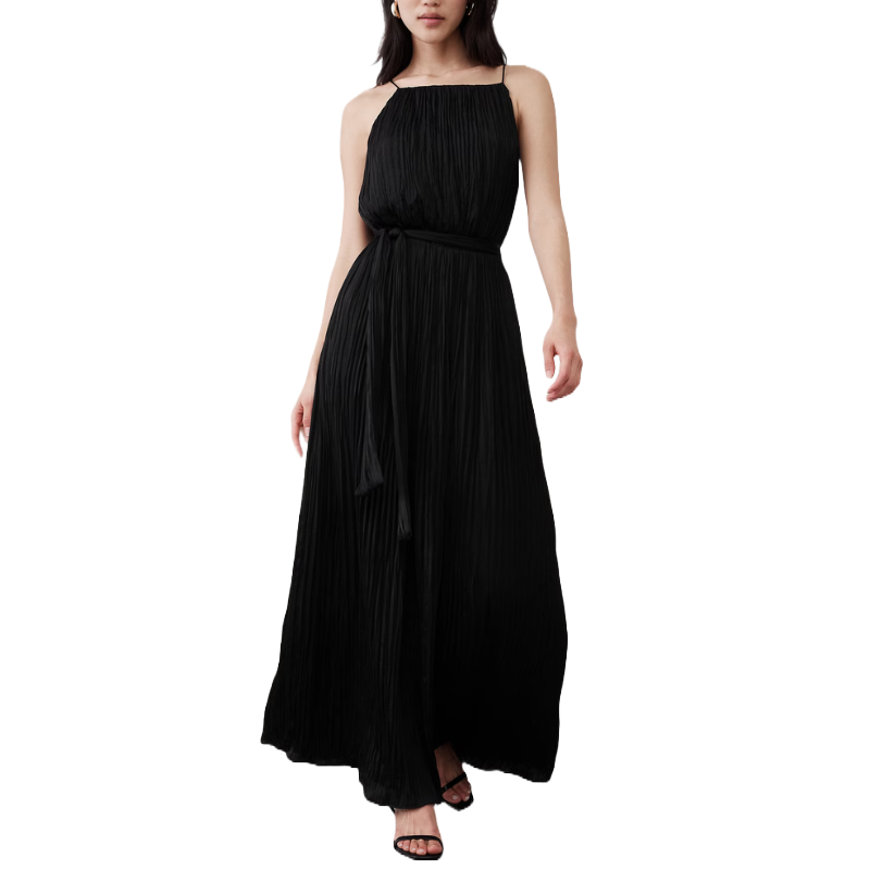 A black sleeveless maxi dress with fine pleats, featuring a high neckline and a matching tie belt at the waist, paired with black strappy heels.