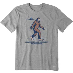 Gray T-shirt featuring an illustration of Bigfoot with a UFO overhead and the text \“I always feel like somebody's squatching me.\“