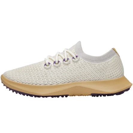 A beige knitted sneaker with white laces, featuring a tan sole and purple accents.