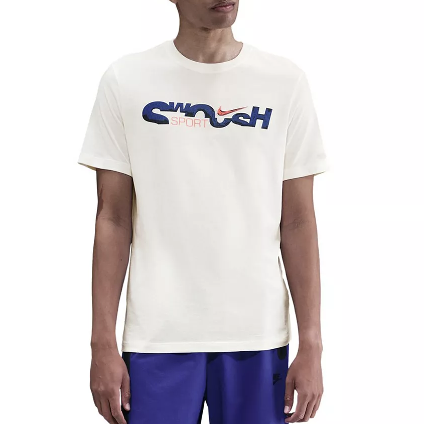 A person wearing a cream-colored T-shirt with \“Swoosh Sport\“ and a Nike logo in blue and red, paired with blue shorts.