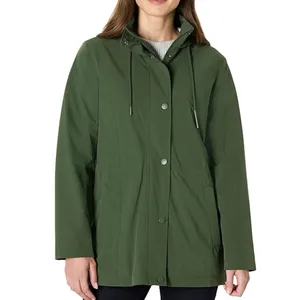 A woman is wearing a green hooded raincoat with snap buttons and a drawstring hood. The coat is paired with dark pants.