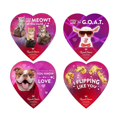 Four heart-shaped Russell Stover chocolate boxes feature playful designs: \“You are MEOWT of this world\“ with cats, \“You are the G.O.A.T.\“ with a goat, \“That Moment When You Know it's Love\“ with a dog, and \“I Flipping Like You\“ with dolphins.