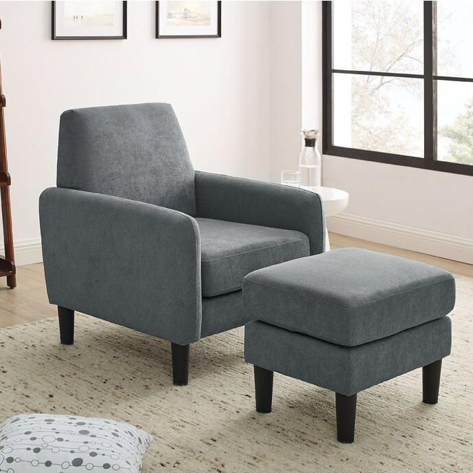 A grey fabric armchair with matching ottoman against a light-colored wall near a window.