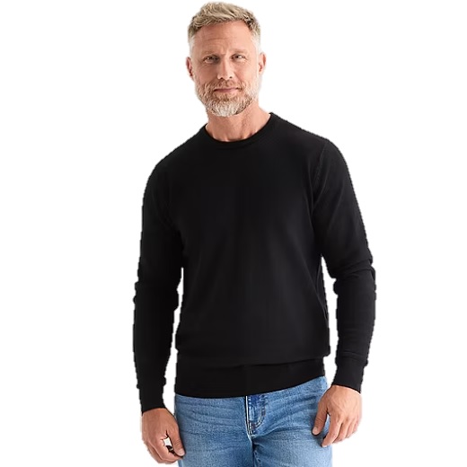 A man is wearing a black long-sleeve shirt and blue jeans, standing against a white background.