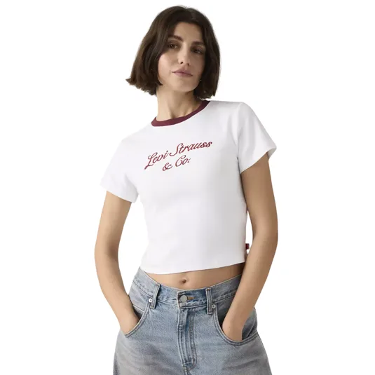 A woman is wearing a white crop top with \“Levi Strauss & Co.\“ written in red, paired with high-waisted blue jeans.