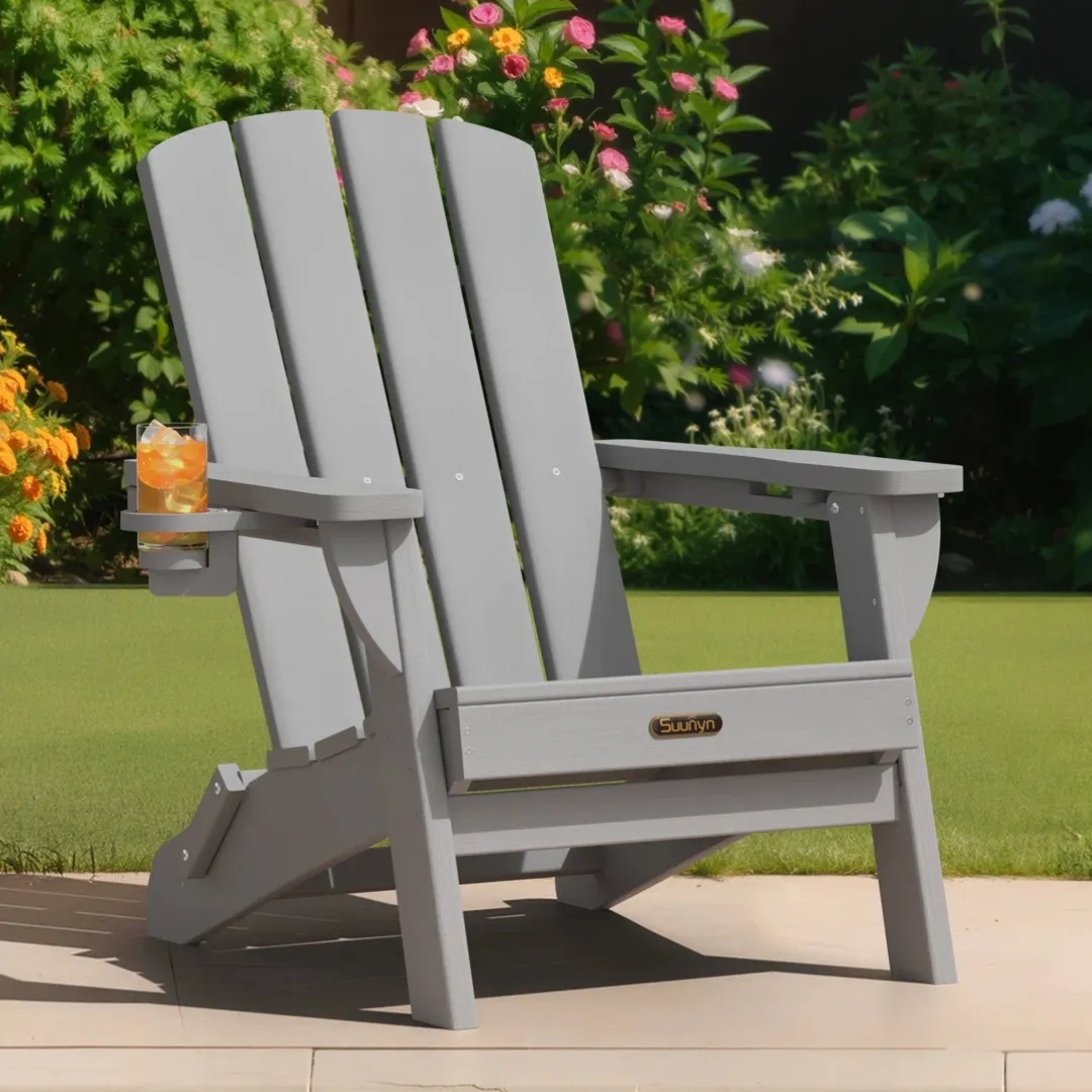 A gray Adirondack chair with a built-in cup holder containing a drink is set on a patio, surrounded by vibrant flowers and greenery.