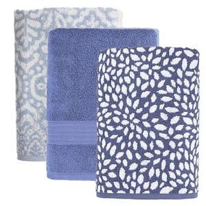 Three towels are stacked vertically: a light blue towel with a floral pattern, a solid blue towel, and a dark blue towel with a white leaf pattern.