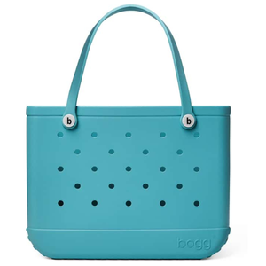 A turquoise Bogg Bag with a perforated design, featuring two handles and branded buttons.