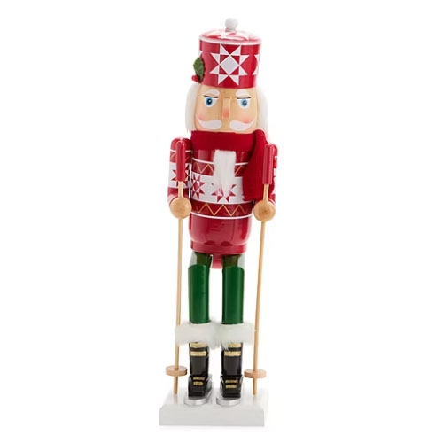 A red and white nutcracker figurine wearing a skiing outfit, complete with skis and poles, adorned with geometric patterns and green boots, stands on a white base.