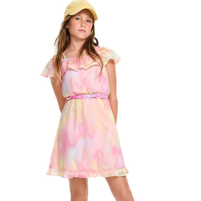 A young girl wearing a pastel-colored, off-shoulder dress with ruffled trim and a pink belt, paired with a yellow cap.