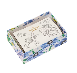 White wallet with floral cut-out designs, placed in a box with a blue and green floral pattern.