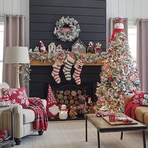 A set of four Christmas-themed miniature ski village houses, intricately designed and decorated with snow, is displayed on a mantelpiece.