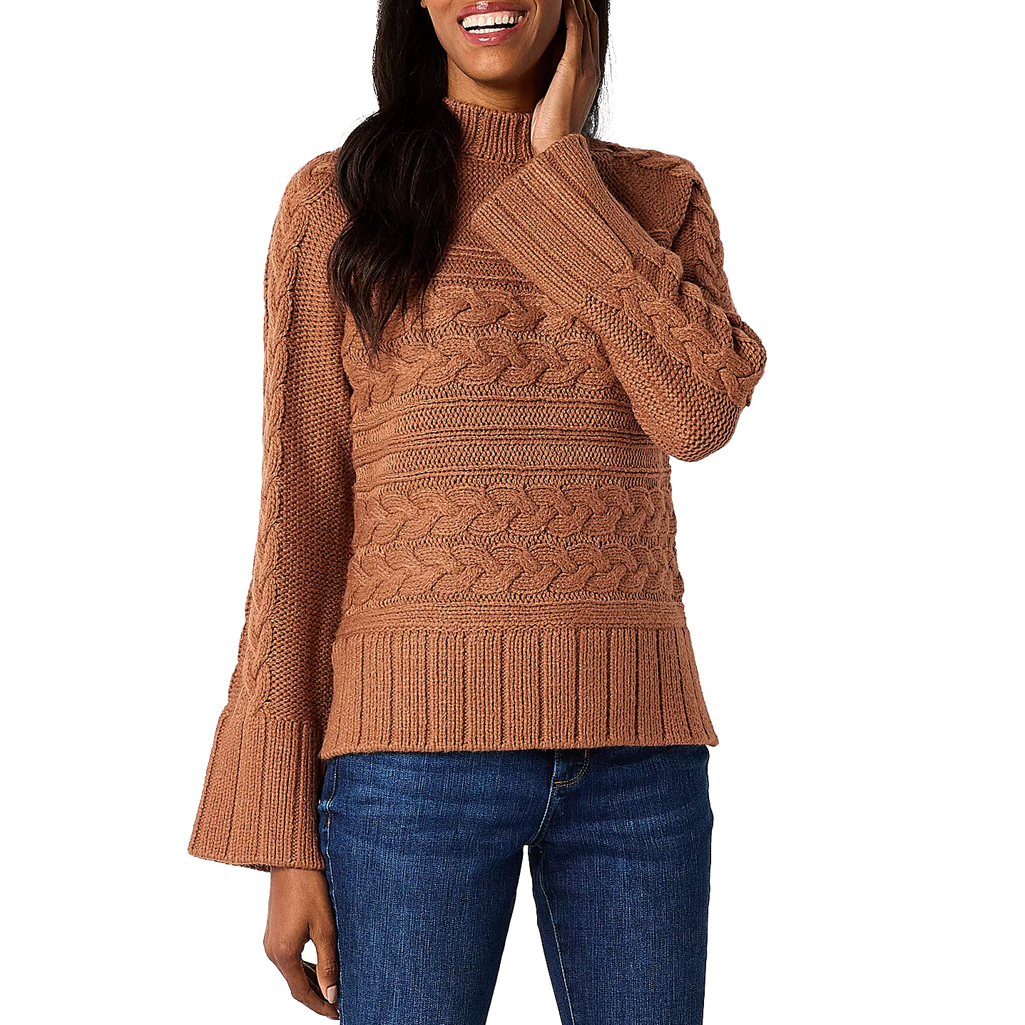 A woman is wearing a brown cable knit sweater paired with blue jeans. The sweater features intricate patterns and flared sleeves.