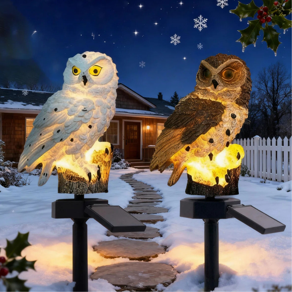 Two decorative solar-powered owl lights illuminate a snowy path in a winter setting, with one owl white and the other brown.