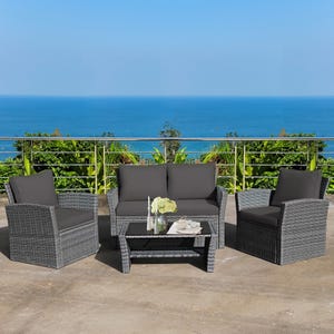Rattan-style patio furniture set with a loveseat, two armchairs, and a coffee table, featuring dark gray cushions, against an ocean backdrop.